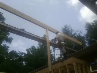 Carpenter setting a ridge beam over a new addition frame — Ice Dam Removal by Roofing Brothers in Manhattan