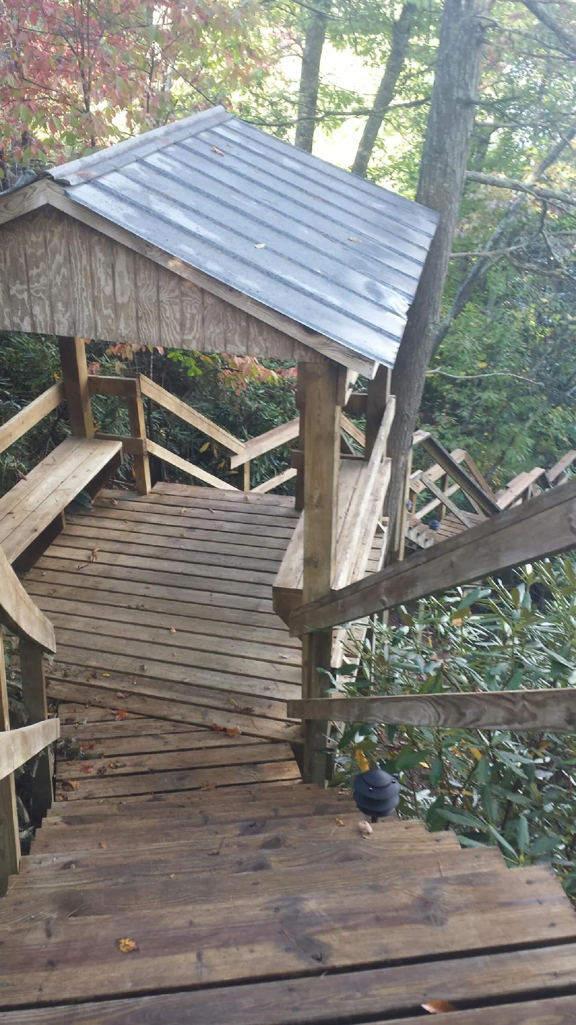 Metal roofed shelter over wooden steps on a wooded walkway — Skylight Repair & Installation work by our crew in Manhattan